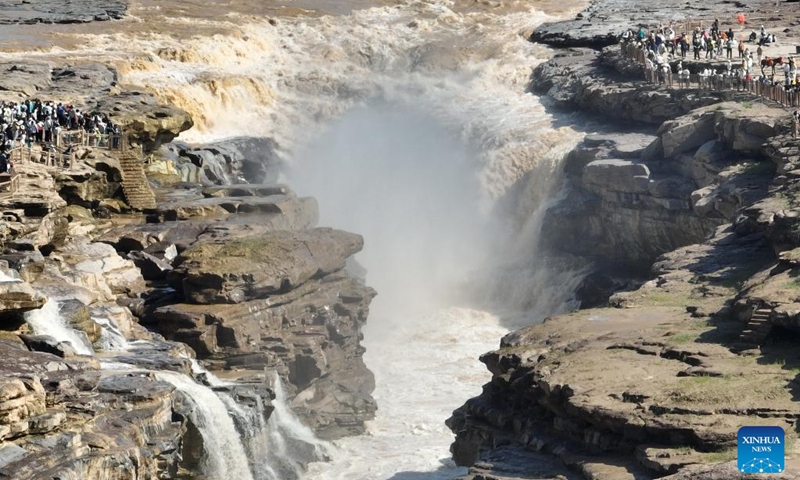 This aerial photo taken on July 3, 2023 shows tourists viewing the scenery of the Hukou Waterfall on the Yellow River, on the border area between north China's Shanxi and northwest China's Shaanxi provinces.(Photo: Xinhua)