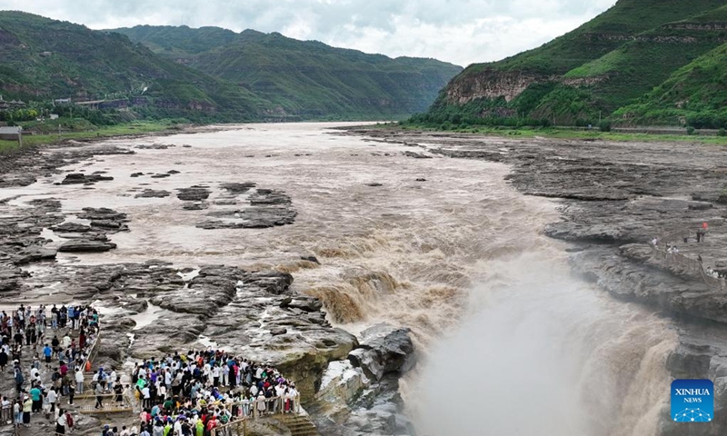 This aerial photo taken on July 3, 2023 shows tourists viewing the scenery of the Hukou Waterfall on the Yellow River, on the border area between north China's Shanxi and northwest China's Shaanxi provinces.(Photo: Xinhua)