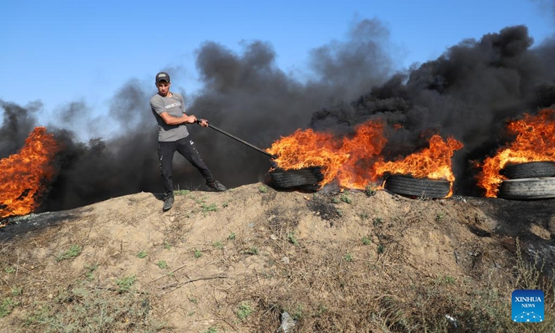 A Palestinian protester burns tires during a protest against the killing of Palestinians near the fence of the Gaza-Israel border, east of Gaza City, on July 3, 2023. At least eight Palestinians were killed and dozens were injured in the northern West Bank city of Jenin on Monday during the Israeli operation launched from midnight throughout the day, said the Palestinian Health Ministry.(Photo: Xinhua)