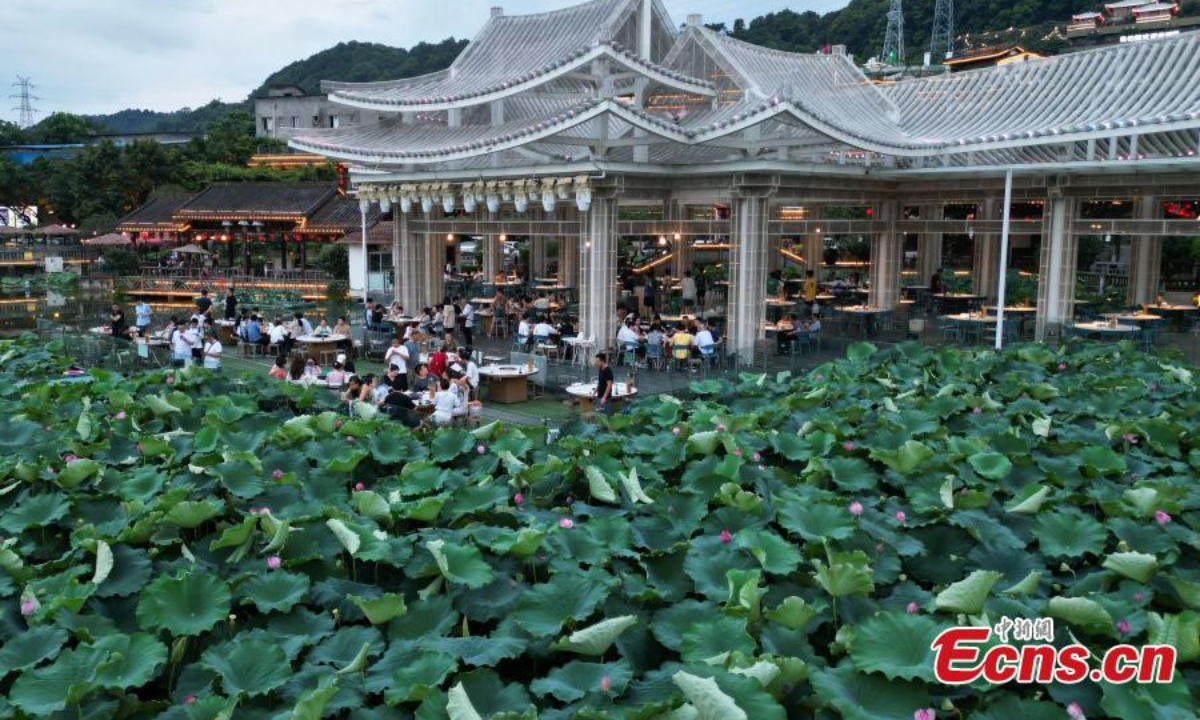 People enjoy hotpot beside a lotus pond filled with blooming lotus flowers in Chongqing, July 12, 2023. Photo: China News Service