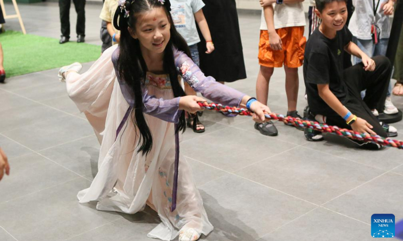 A girl takes part in a traditional tug-of-war game at a night fair at Minhang Museum of Shanghai in east China to experience the traditional Mongolian custom, July 21, 2023. (Xinhua/Xin Mengchen)