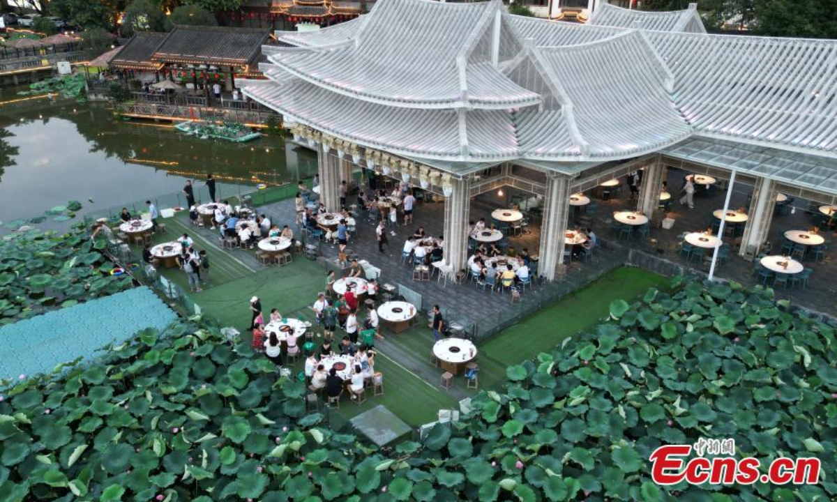 People enjoy hotpot beside a lotus pond filled with blooming lotus flowers in Chongqing, July 12, 2023. Photo: China News Service