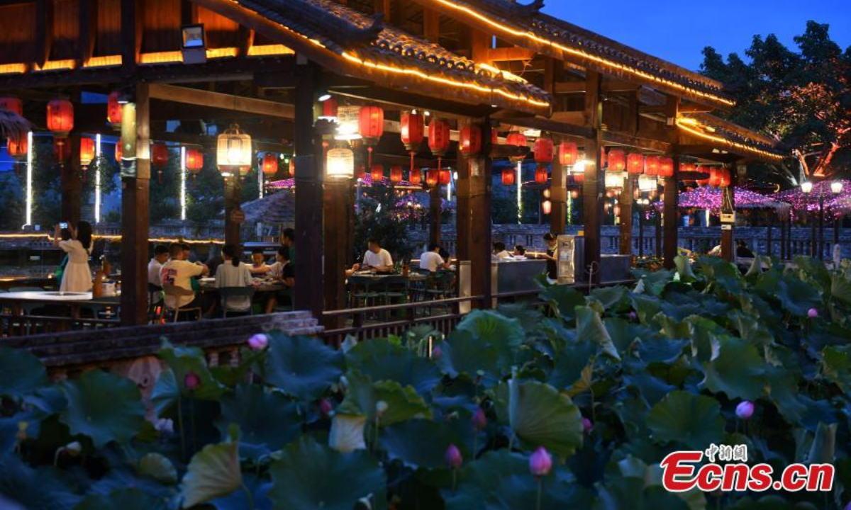 People enjoy hotpot beside a lotus pond filled with blooming lotus flowers in Chongqing, July 12, 2023. Photo: China News Service