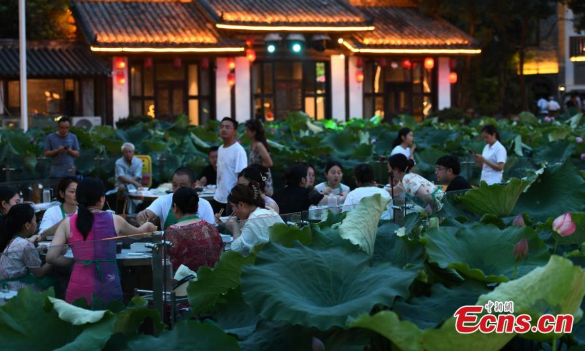 People enjoy hotpot beside a lotus pond filled with blooming lotus flowers in Chongqing, July 12, 2023. Photo: China News Service