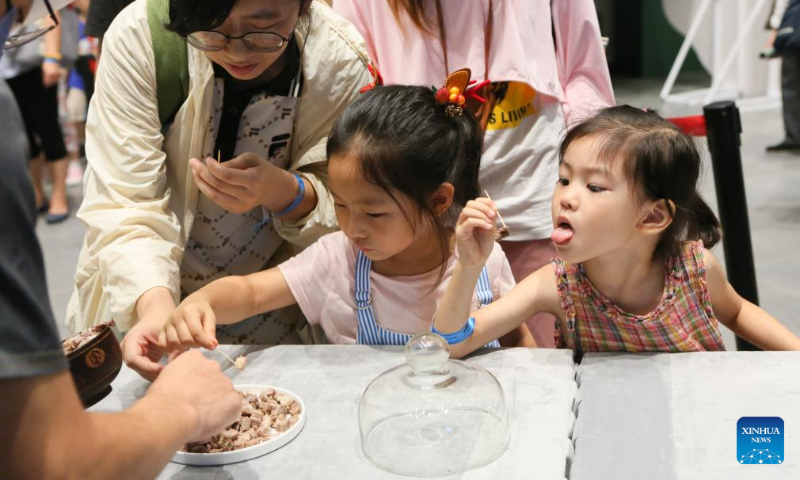Visitors taste Mongolian specialty food at a night fair at Minhang Museum of Shanghai in east China to experience the traditional Mongolian custom, July 21, 2023. (Xinhua/Xin Mengchen)