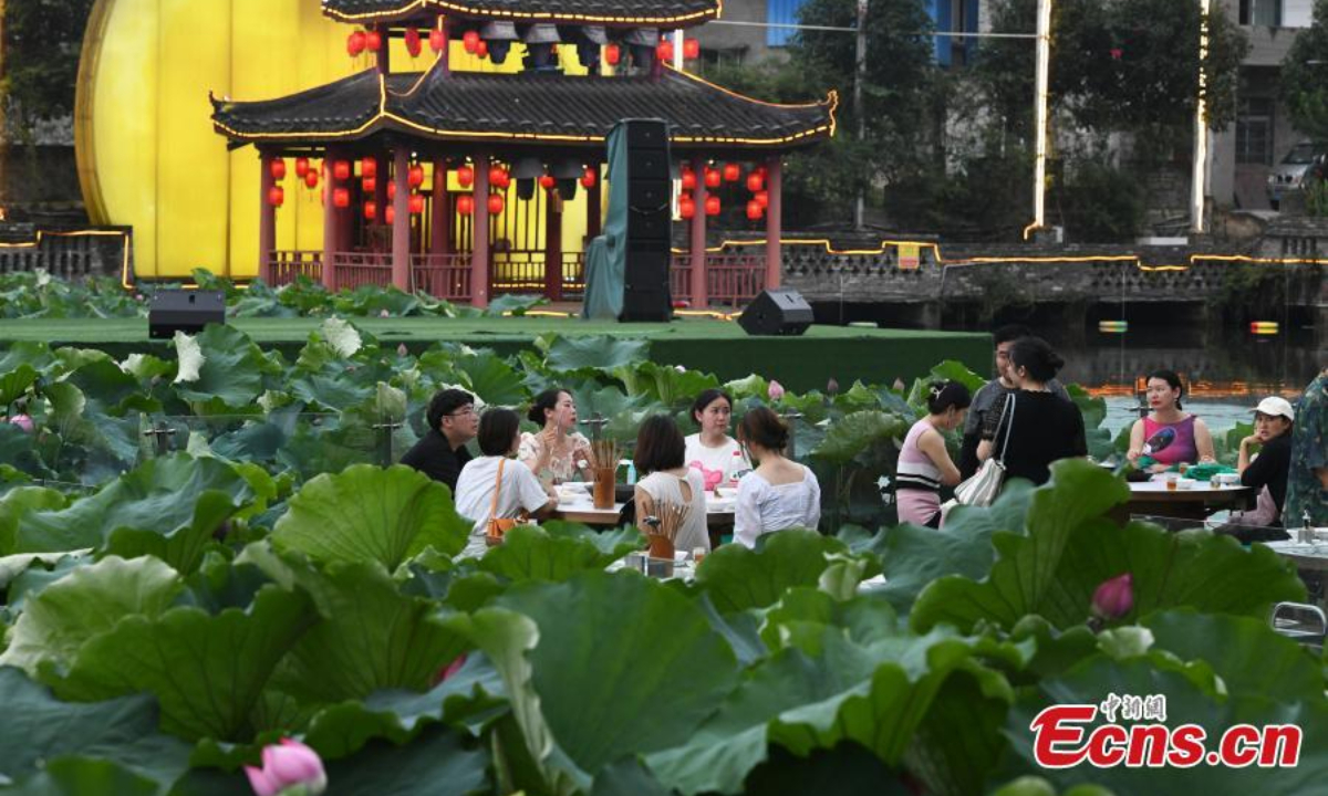 People enjoy hotpot beside a lotus pond filled with blooming lotus flowers in Chongqing, July 12, 2023. Photo: China News Service