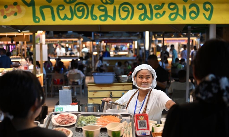 People buy snacks at a Thai food stall of the Baishamen cultural and creative bazaar in Haikou, south China's Hainan Province, July 5, 2023.(Photo: Xinhua)