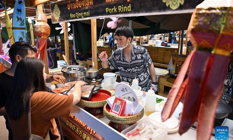 People buy snacks at a Thai food stall of the Baishamen cultural and creative bazaar in Haikou, south China's Hainan Province, July 5, 2023.(Photo: Xinhua)