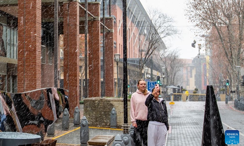 People take photos as snow falls in Melrose Arch in Johannesburg, South Africa, on July 10, 202(Photo: Xinhua)