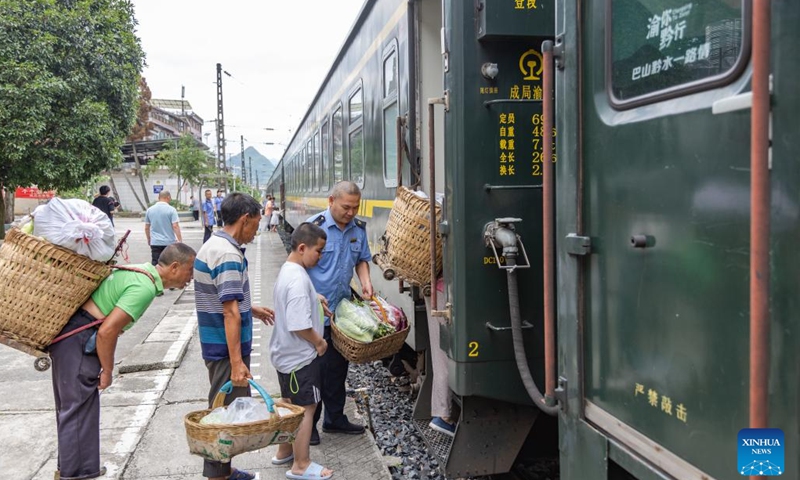 A staff member helps local villagers board train No. 5630 from Zunyi, southwest China's Guizhou Province to southwest China's Chongqing Municipality, July 11, 2023. Trains No.5630 and 5629 are slow trains operating between Zunyi of Guizhou Province and Chongqing Municipality in southwest China.(Photo: Xinhua)