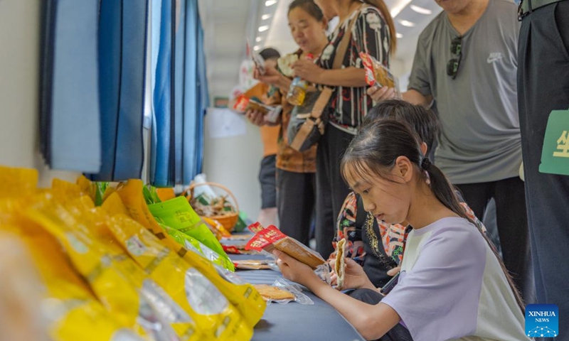 Passengers shop for local specialties on train No. 5630 from Zunyi, southwest China's Guizhou Province to southwest China's Chongqing Municipality, July 11, 2023. Trains No.5630 and 5629 are slow trains operating between Zunyi of Guizhou Province and Chongqing Municipality in southwest China.(Photo: Xinhua)