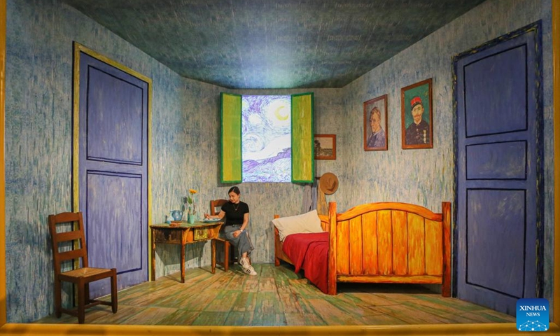 A woman poses for photos during the immersive exhibition Van Gogh Alive: the experience at the World Expo Museum at night in Shanghai, east China, July 16, 2023. The World Expo Museum in east China's Shanghai extends its opening hours on every Friday, Saturday, Sunday and holidays from May 12 to Sept. 10, 2023.(Photo: Xinhua)