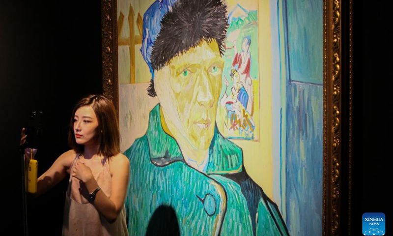 A woman poses for a photo during the immersive exhibition Van Gogh Alive: the experience at the World Expo Museum at night in Shanghai, east China, July 16, 2023. The World Expo Museum in east China's Shanghai extends its opening hours on every Friday, Saturday, Sunday and holidays from May 12 to Sept. 10, 2023.(Photo: Xinhua)