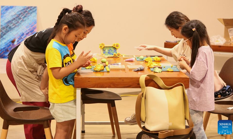 Children make sunflower-themed clay photo frames at the World Expo Museum at night in Shanghai, east China, July 16, 2023. The World Expo Museum in east China's Shanghai extends its opening hours on every Friday, Saturday, Sunday and holidays from May 12 to Sept. 10, 2023.(Photo: Xinhua)