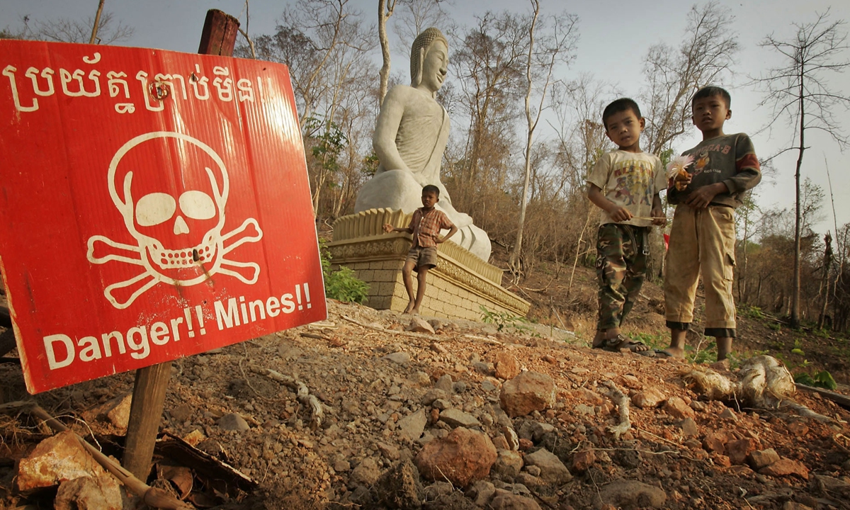 Children play near a landmine warning and a Buddhist shrine in Cambodia. Photo: VCG