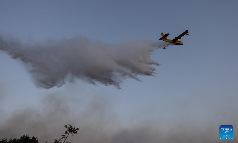 This photo taken on July 18, 2023 shows a firefighting aircraft dropping water to put out a wildfire in Pournari, a western suburb of Athens, Greece. Hundreds of Greek firefighters continued for a second day on Tuesday to battle two major wildfires near Dervenochoria, some 30 km northwest of Athens, and near the seaside resort of Loutraki, about 80 km southwest of the capital, authorities said.(Photo: Xinhua)