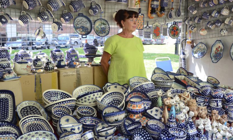A woman sells local porcelain at St. Dominic's Fair in Gdansk, Poland, July 30, 2023. The St. Dominic's Fair is held in Poland's port city of Gdansk from July 22 to Aug. 13 this year. (Xinhua/Chen Chen)