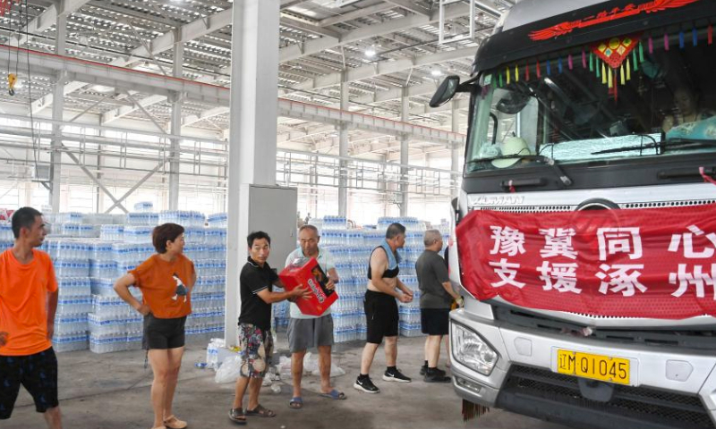 Staff members and volunteers transfer the donated relief supplies at a storage site of relief supplies in Zhuozhou, north China's Hebei Province, Aug. 5, 2023. A large number of donated relief supplies from all over the country arrived in Zhuozhou on Saturday, supporting local people affected by rainstorms and floods. (Xinhua/Mu Yu)