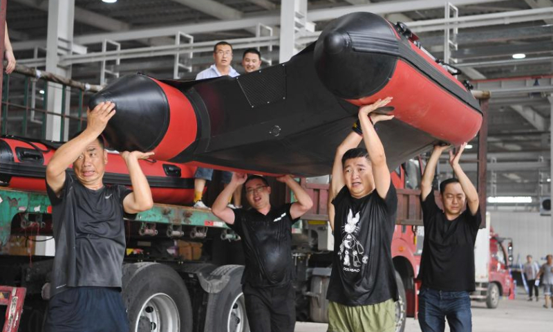 Staff members and volunteers transfer a donated speedboat at a storage site of relief supplies in Zhuozhou, north China's Hebei Province, Aug. 5, 2023. A large number of donated relief supplies from all over the country arrived in Zhuozhou on Saturday, supporting local people affected by rainstorms and floods. (Xinhua/Mu Yu)