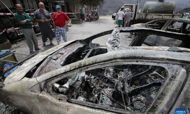 People inspect vehicles burned in a wildfire in Bejaia Province, Algeria, on July 25, 2023. The death toll from wildfires in northern Algeria has risen to 34, including 10 soldiers, the Interior Ministry said in an update on Monday. The fires started overnight on Sunday mainly in the provinces of Bejaia, Jijel, and Bouira, but quickly spread due to strong winds, causing significant damage. (Xinhua)