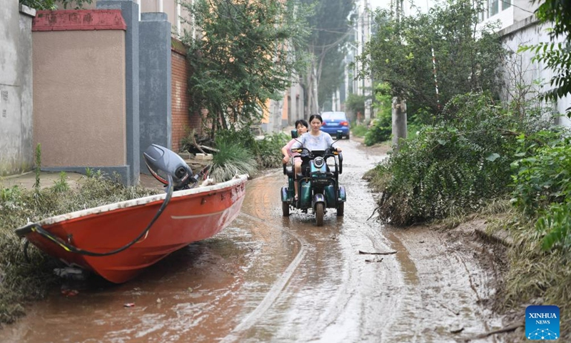 Residents ride an electric tricycle in Gaojiazhuang Village, Matou Town of Zhuozhou, north China's Hebei Province, Aug. 3, 2023. Zhuozhou City is an area in Hebei that has been severely affected by rain-triggered floods. Local authorities set up 28 emergency rescue teams with a total of 8,755 people to help with the rescue and relief efforts. They worked in collaboration with soldiers stationed there and professional rescue teams.(Photo: Xinhua)