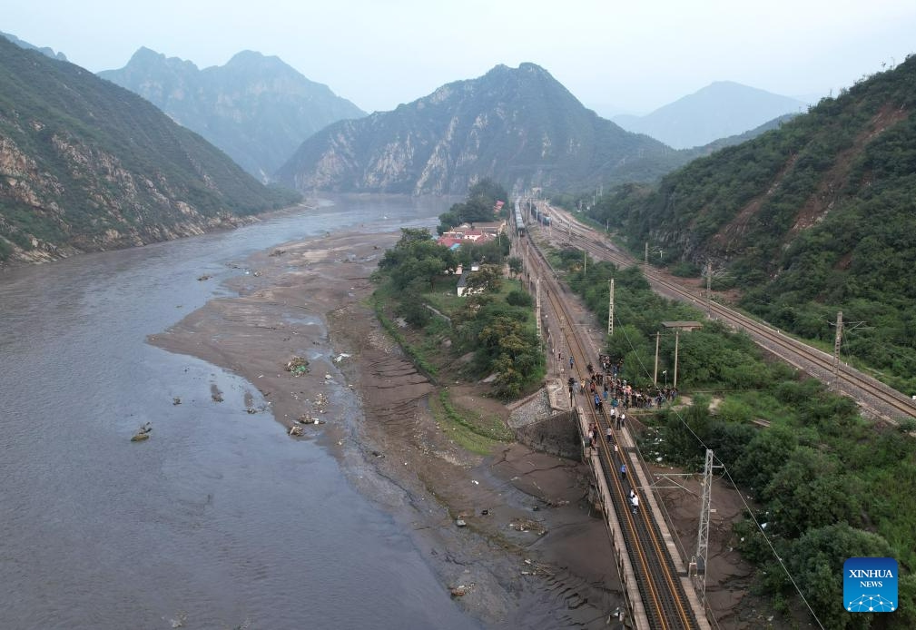 This aerial photo taken on Aug. 2, 2023 shows stranded passengers walking to the transshipment train with the help of rescuers in Mentougou District of Beijing, capital of China. The last batch of stranded passengers of trains Z180 and K396 arrived at the Fengtai Railway Station in Beijing early in the morning on Aug. 3.(Photo: Xinhua)