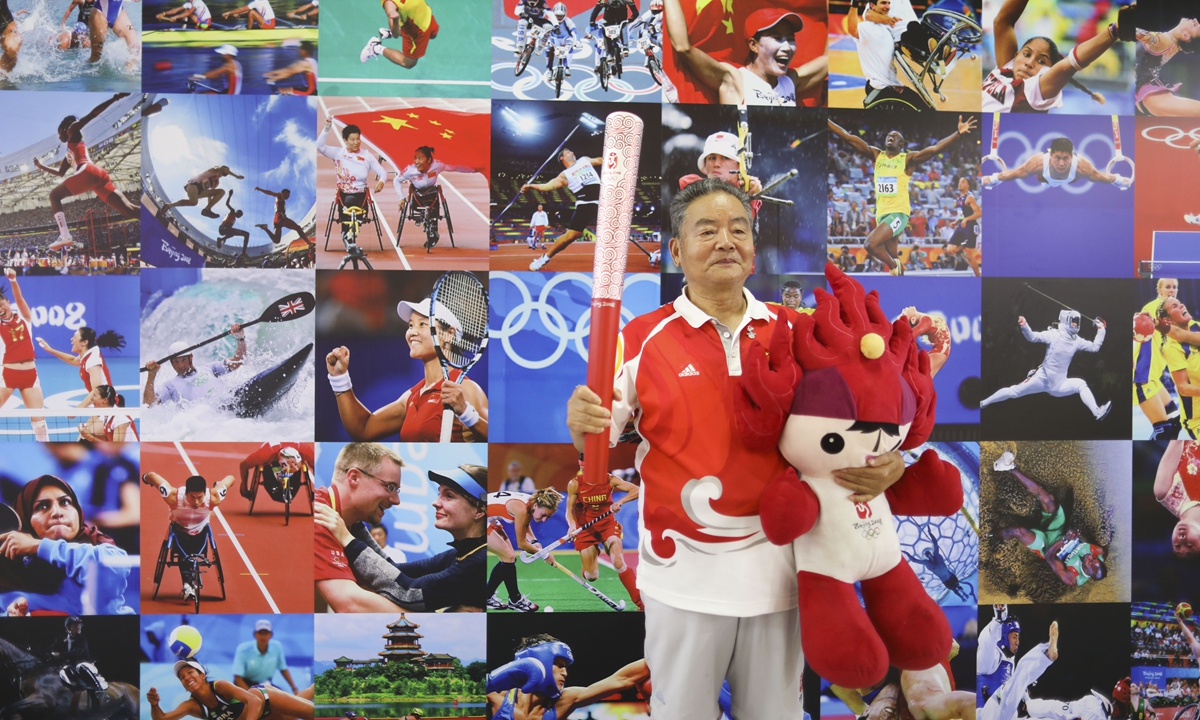 A senior citizen has a photo taken in front of a photo wall in Beijing to mark the 15th anniversary of Beijing 2008 Olympics.