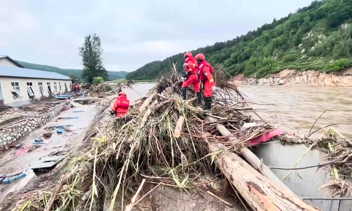 Firefighters remove trees destroyed by flooding from the road in Hailin, Northeast China's Heilongjiang Province, on August 7, 2023. Photo: VCG