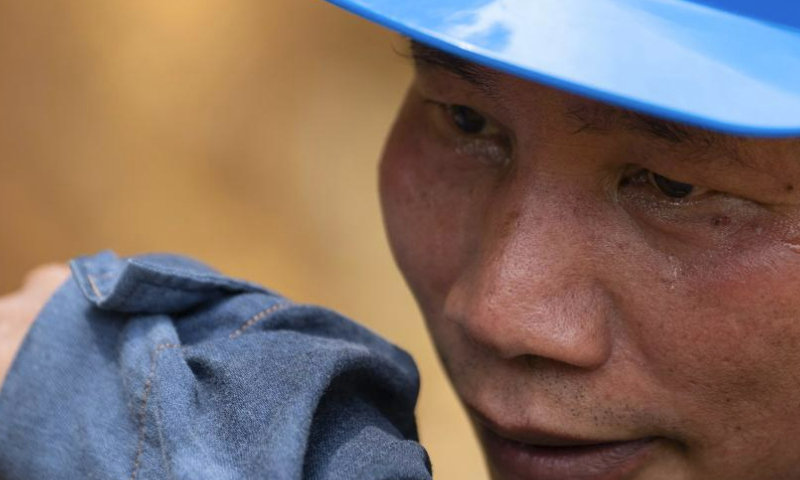 Wen Xianwen wipes his sweat during his maintenance work in Pingxiang, south China's Guangxi Zhuang Autonomous Region, Aug. 10, 2023. Wen Xianwen, Yao Zhengqiang, Deng Yiqiang and Li Yingxing are members of a team of maintenance personnel from the Guangxi branch of China Southern Power Grid's Pingxiang power supply station. Workers of the team, which was founded in 1974, have patrolled nearly 250,000-kilometer-long power transmission lines over the past 49 years. Led by Wen at present, the team has entered its fourth generation.