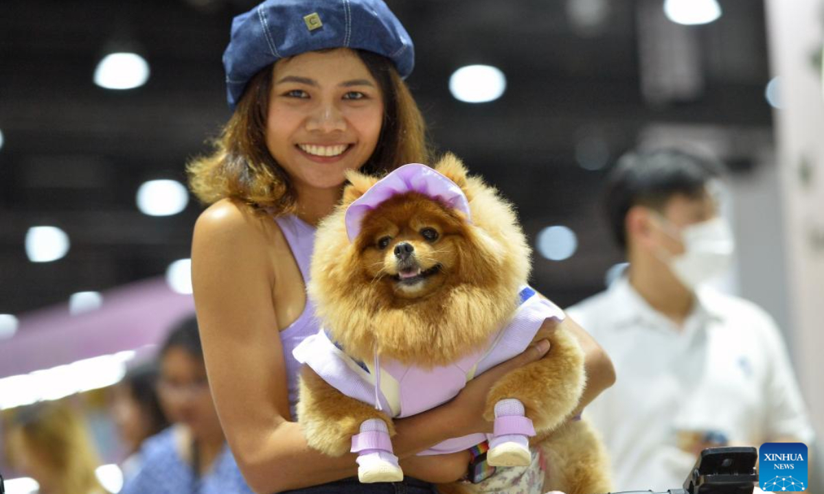 A visitor poses for photos with a pet dog during a pet expo in Bangkok, Thailand, Aug 10, 2023. Photo:Xinhua