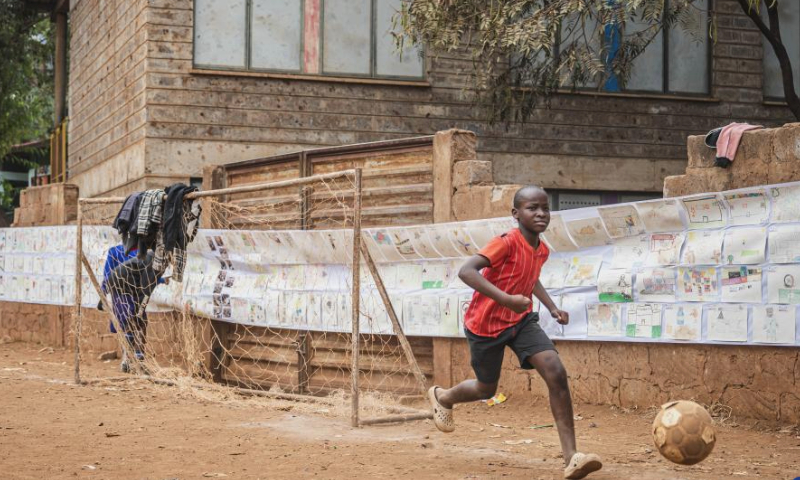 A child plays football during a carnival in Mathare slum of Nairobi, Kenya, Aug. 11, 2023. A slum carnival, organized by non-governmental organization Dream Building Service Association (DBSA), kicked off in the Mathare slum of Nairobi on Friday. Featuring art exhibitions, football matches and other activities, this carnival attracted numerous local residents. (Xinhua/Wang Guansen)
