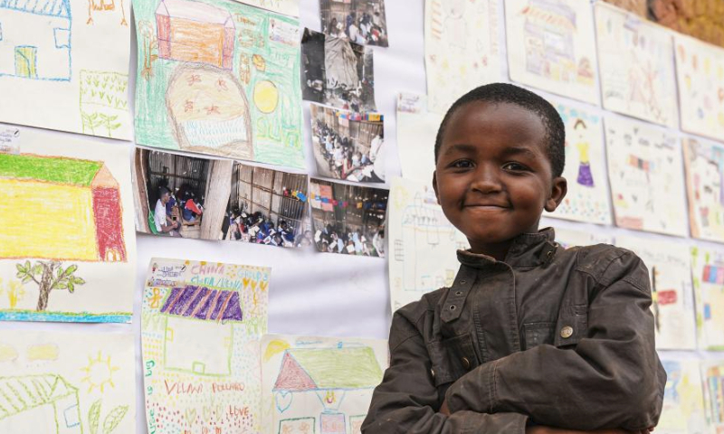 A child poses for photos in front of paintings exhibited during a carnival in Mathare slum of Nairobi, Kenya, Aug. 11, 2023. A slum carnival, organized by non-governmental organization Dream Building Service Association (DBSA), kicked off in the Mathare slum of Nairobi on Friday. Featuring art exhibitions, football matches and other activities, this carnival attracted numerous local residents. (Xinhua/Han Xu)