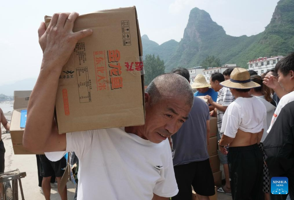Villagers receive rice in Shangzhuang Village of Sanpo Town, Laishui County, north China's Hebei Province, Aug. 9, 2023. Affected by heavy rainfall, some villages in Laishui County encountered traffic and communication disruptions. Local authorities have made every effort in mending infrastructure damaged by flood while delivering disaster relief supplies purchased by the government and donated by all walks of life to flood-affected residents.(Photo: Xinhua)