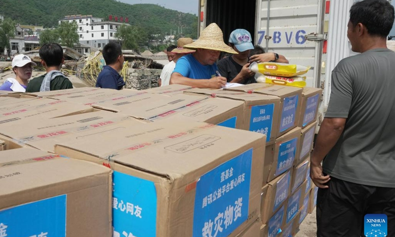 Villagers receive rice and flour in Shangzhuang Village of Sanpo Town, Laishui County, north China's Hebei Province, Aug. 9, 2023. Affected by heavy rainfall, some villages in Laishui County encountered traffic and communication disruptions. Local authorities have made every effort in mending infrastructure damaged by flood while delivering disaster relief supplies purchased by the government and donated by all walks of life to flood-affected residents.(Photo: Xinhua)