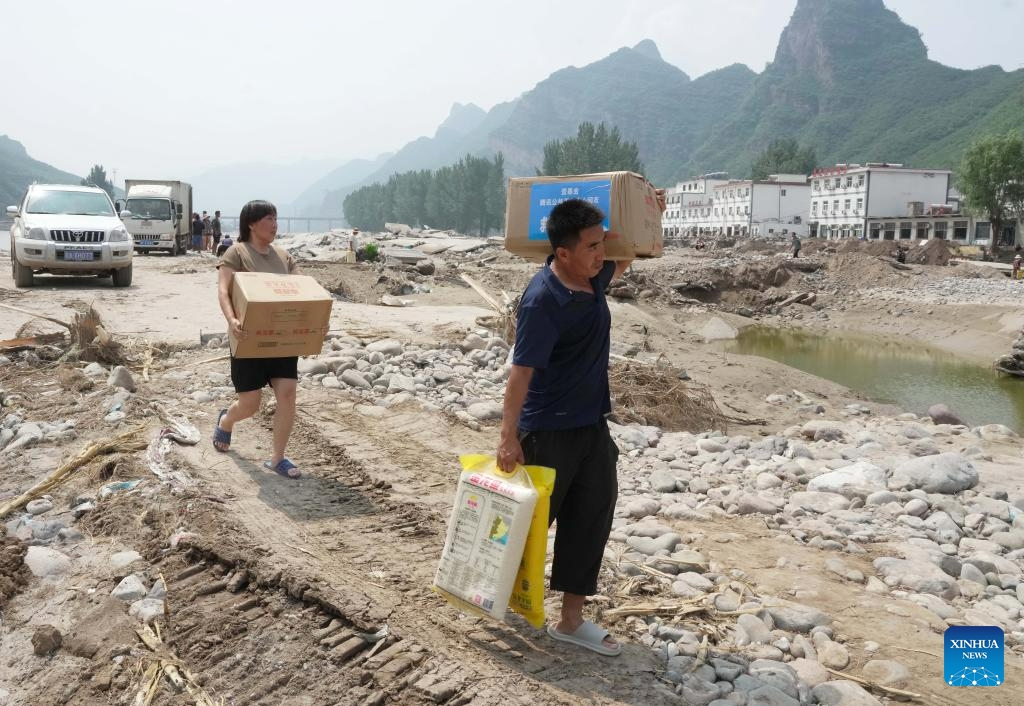 Villagers carrying disaster relief rice walk back home in Shangzhuang Village of Sanpo Town, Laishui County, north China's Hebei Province, Aug. 9, 2023. Affected by heavy rainfall, some villages in Laishui County encountered traffic and communication disruptions. Local authorities have made every effort in mending infrastructure damaged by flood while delivering disaster relief supplies purchased by the government and donated by all walks of life to flood-affected residents.(Photo: Xinhua)