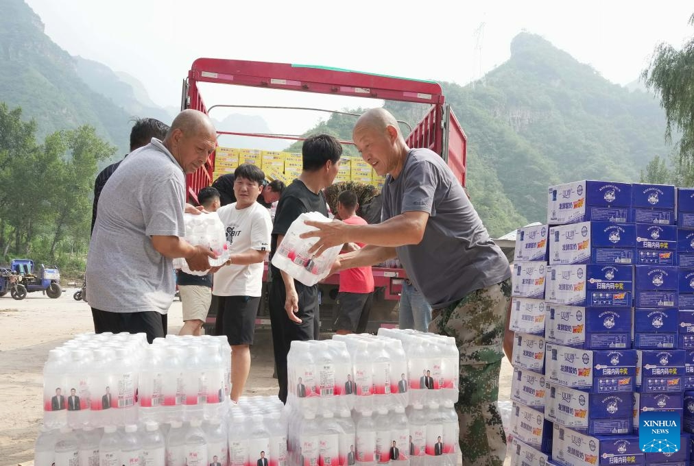 Villagers unload food and bottled water from a truck in Longmen Township of Laishui County, north China's Hebei Province, Aug. 10, 2023. Affected by heavy rainfall, some villages in Laishui County encountered traffic and communication disruptions. Local authorities have made every effort in mending infrastructure damaged by flood while delivering disaster relief supplies purchased by the government and donated by all walks of life to flood-affected residents.(Photo: Xinhua)