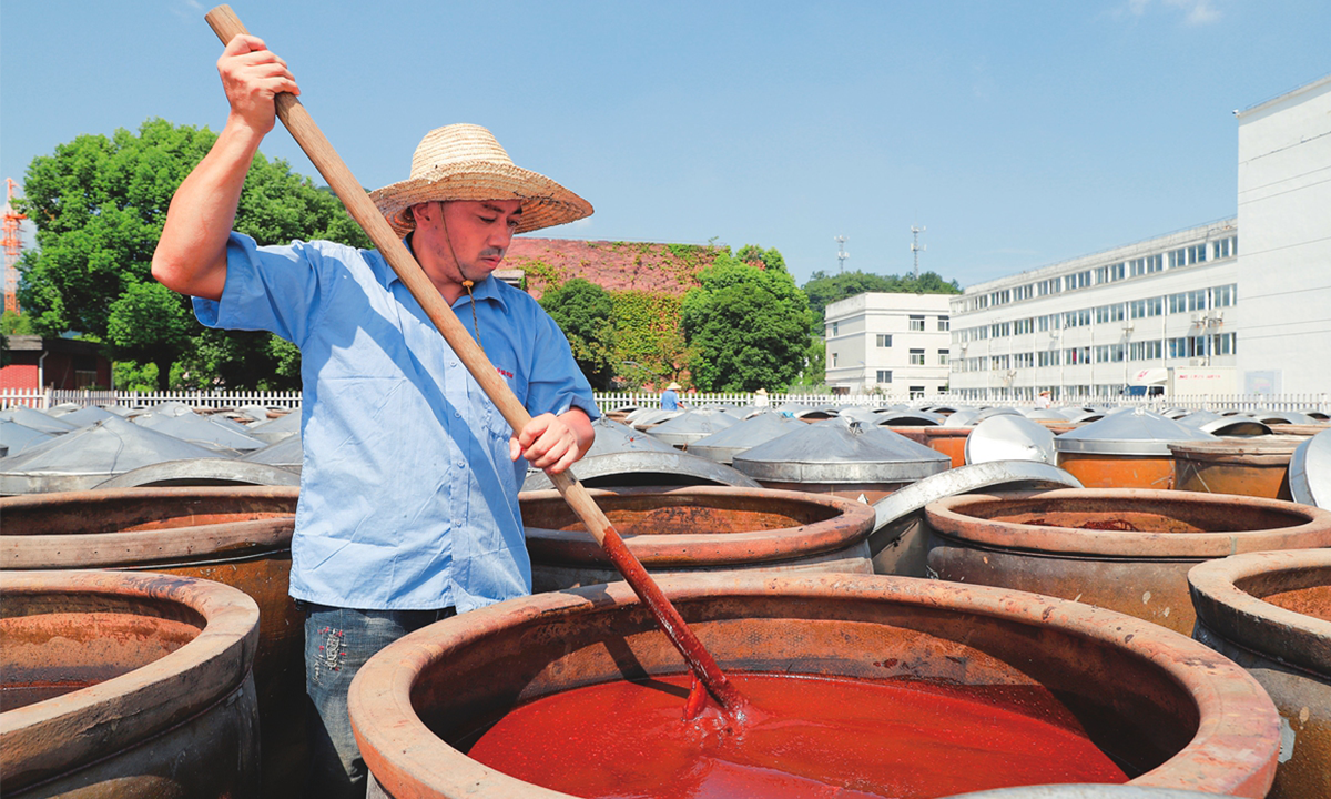 A staff member mixes soy sauce in a jar during the production process in Shaoxing, East China’s Zhejiang Province on August 13, 2023. Shaoxing has more than 20 enterprises in this industry with annual output of 2 million kilograms. The production technology of local soy sauce with a total production period of 180 days was included in the intangible cultural heritage list of Zhejiang Province in 2009. Photo: cnsphoto