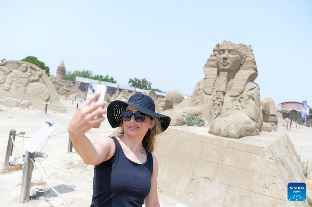 A visitor takes a selfie with a sand sculpture at the Antalya Sand Sculpture Museum in Antalya, Türkiye, Aug. 16, 2023.(Photo: Xinhua)
