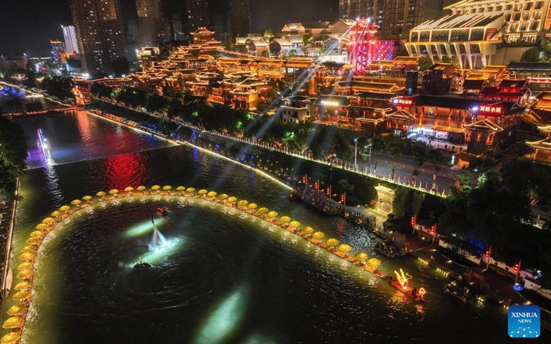 This aerial photo taken on Aug. 18, 2023 shows people taking bamboo rafts on the Gongshui River in Xuan'en County of Enshi Tujia and Miao Autonomous Prefecture, central China's Hubei Province. A series of activities have been held to boost the nighttime economy in the scenic area of Xuan'en County including sightseeing trips on the Gongshui River and night fairs along the river. (Xinhua/Cheng Min)