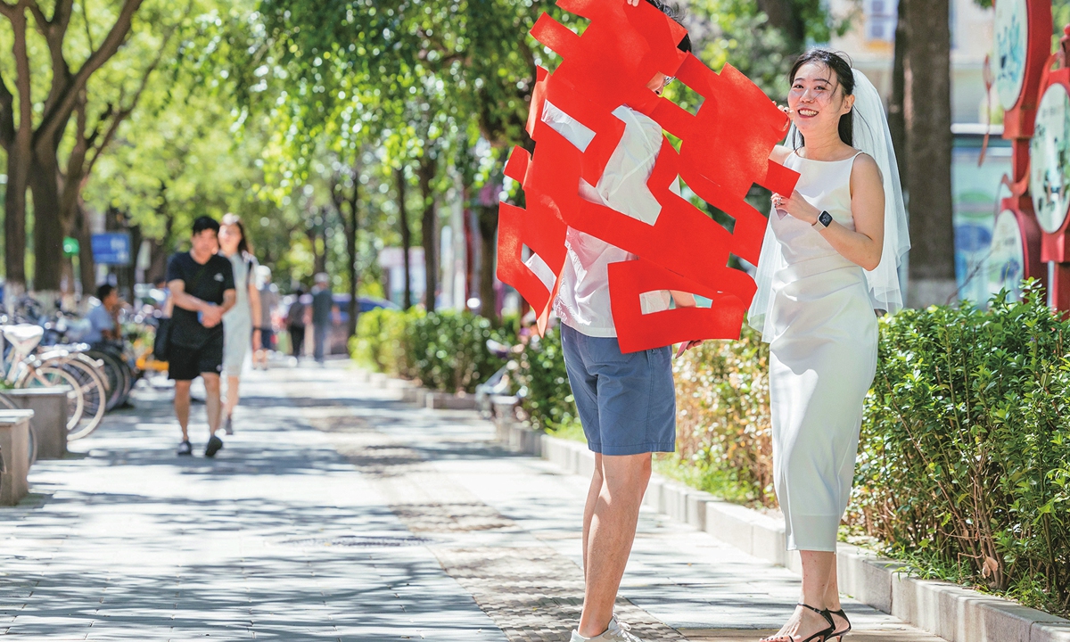 Newlyweds hold a giant paper cutting shaped as the Chinese character xi or “double happiness,” after getting their marriage certificate at the Haidian district civil affairs bureau in Beijing on the day of the Qixi Festival, the Chinese Valentine’s day which fell this year on August 22, 2023. Photo: Li Hao/Global Times