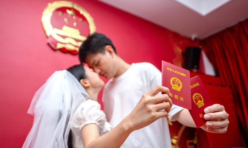 A couple pose for photos with their marriage certificates at a marriage registration office in Huzhou, east China's Zhejiang Province, Aug. 22, 2023. Many couples chose to get married on Tuesday, which is the traditional Qixi Festival, or the Chinese Valentine's Day.(Photo: Xinhua)