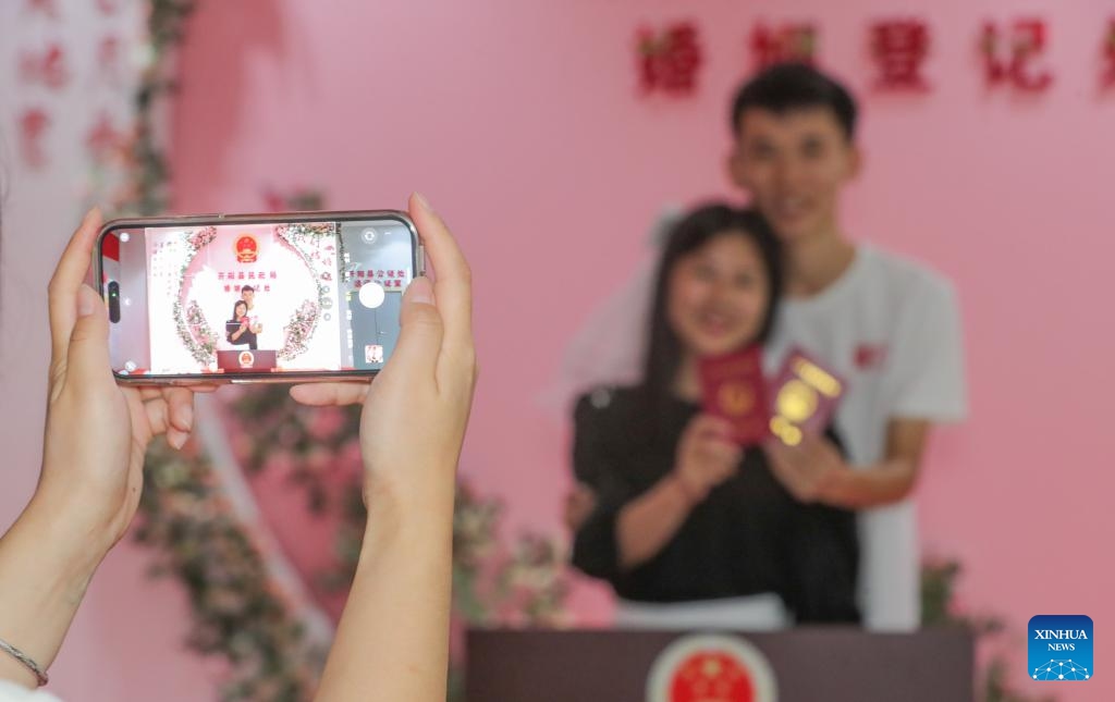 A couple pose for photos with their marriage certificates at a marriage registration office in Kaiyang County, southwest China's Guizhou Province, Aug. 22, 2023. Many couples chose to get married on Tuesday, which is the traditional Qixi Festival, or the Chinese Valentine's Day.(Photo: Xinhua)