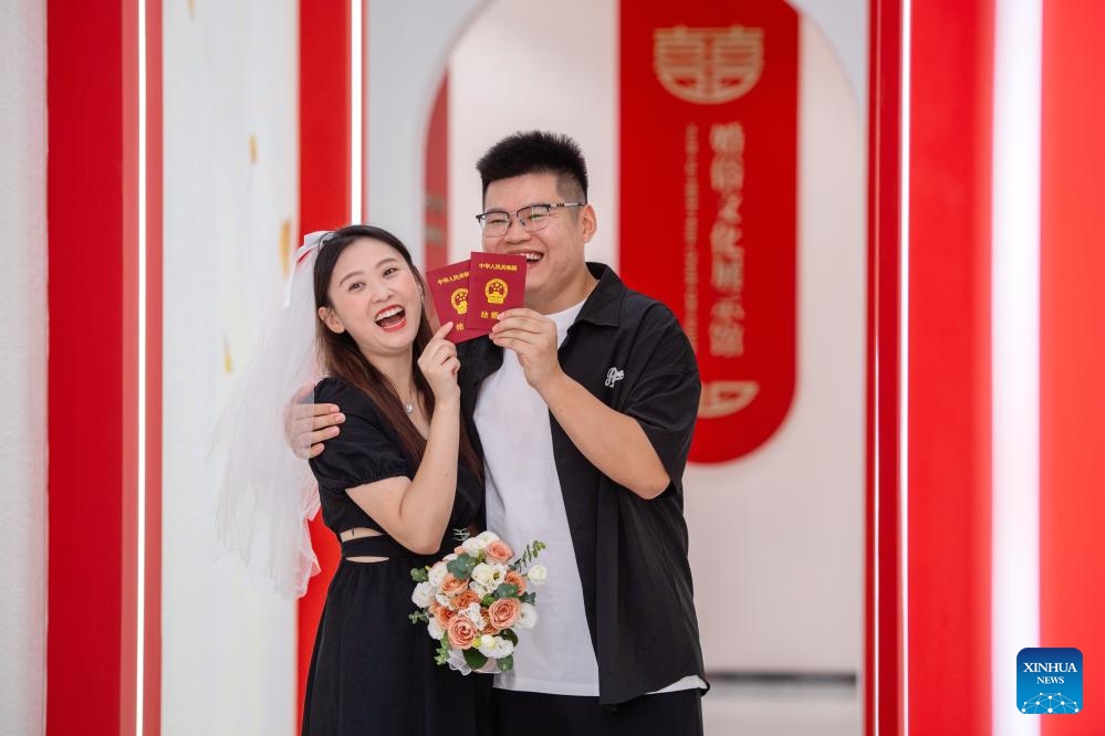 A couple pose for photos with their marriage certificates at a marriage registration office in Huzhou, east China's Zhejiang Province, Aug. 22, 2023. Many couples chose to get married on Tuesday, which is the traditional Qixi Festival, or the Chinese Valentine's Day.(Photo: Xinhua)
