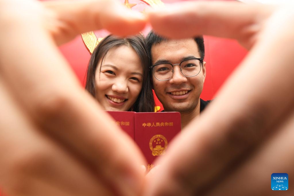 A couple pose for photos with their marriage certificates at a marriage registration office in Shijiazhuang, north China's Hebei Province, Aug. 22, 2023. Many couples chose to get married on Tuesday, which is the traditional Qixi Festival, or the Chinese Valentine's Day.(Photo: Xinhua)