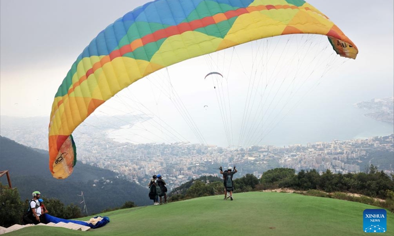 A paragliding tourist and a pilot prepare to take off from a hilltop launch site near Jounieh Bay, Lebanon, on Aug. 26, 2023. Photo: Xinhua