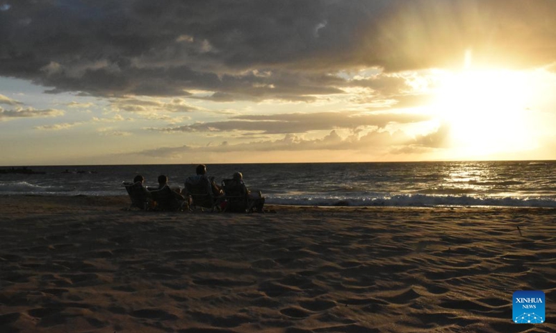 Photo taken on Aug. 23, 2023 shows people sitting on an empty beach during sunset in Maui, Hawaii, the United States. The devastating wildfires that ravaged the Hawaiian island of Maui were a bitter blow to the island's tourism industry, but local residents and business leaders expect more tourists will come back as the island embarks on a long road ahead for recovery. Photo: Xinhua