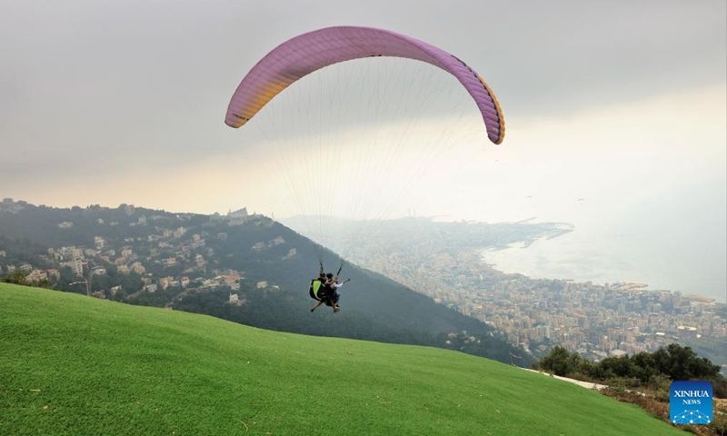 A paragliding tourist and a pilot take off from a hilltop launch site near Jounieh Bay, Lebanon, on Aug. 26, 2023. Photo: Xinhua