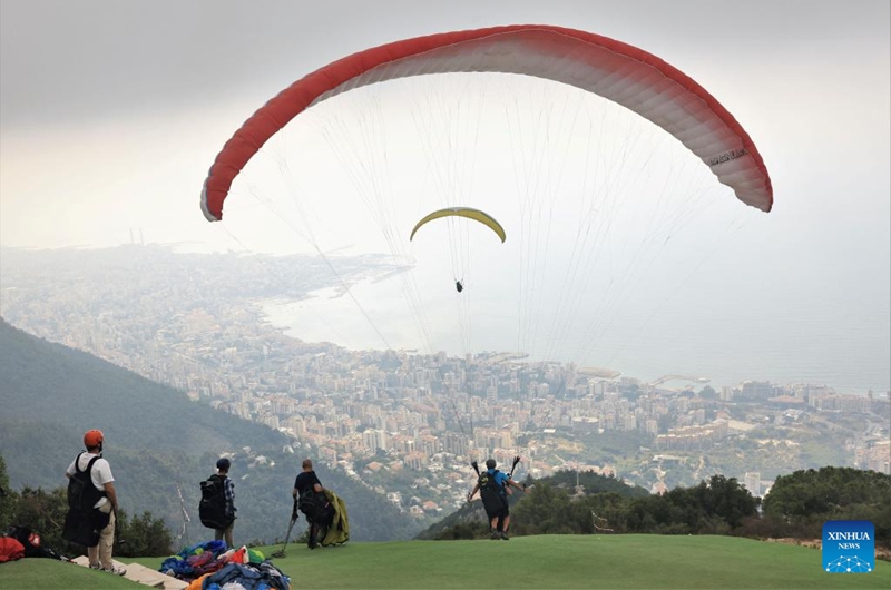 A paragliding tourist and a pilot prepare to take off from a hilltop launch site near Jounieh Bay, Lebanon, on Aug. 26, 2023. Photo: Xinhua