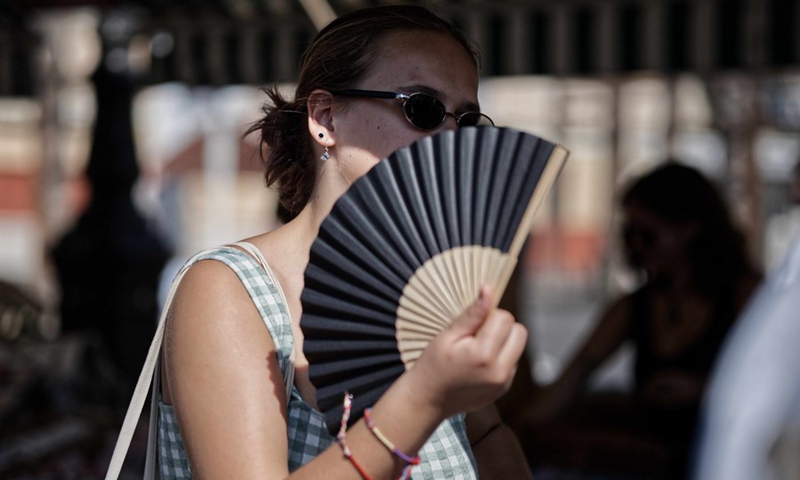 A woman walks on the street with a fan amid a heatwave in Nice, southern France, Aug. 22, 2023. Photo: Xinhua