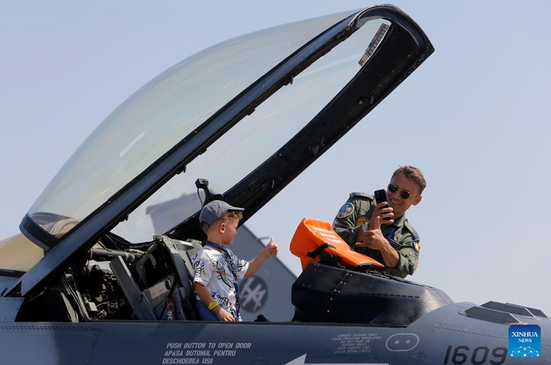 A pilot takes photos of a child visiting a military airplane of Romanian Air Force on display during the 2023 Bucharest International Air Show & General Aviation Exhibition in Bucharest, Romania, Aug. 26, 2023. Photo: Xinhua